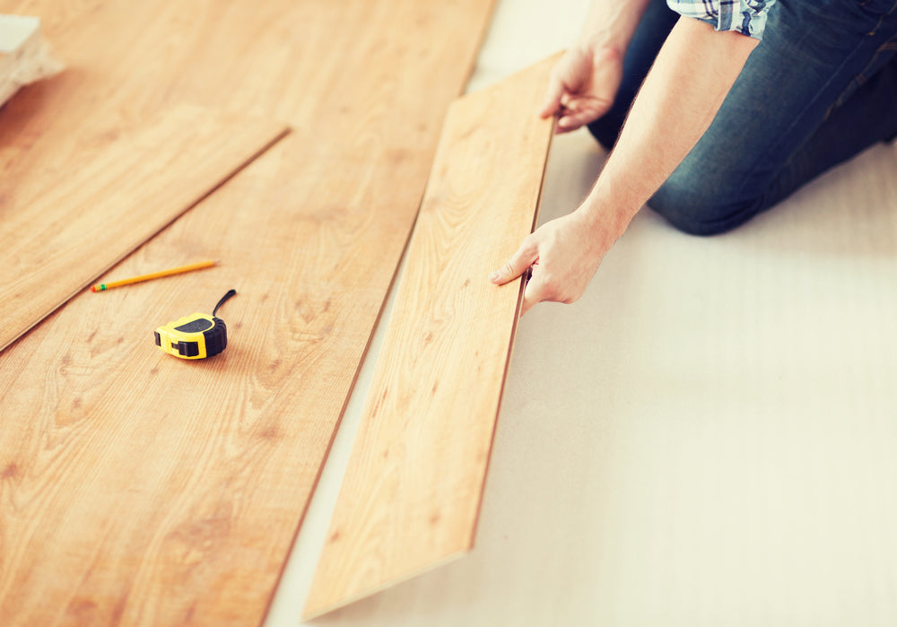 repair, building and home concept - close up of male hands intalling wood flooring