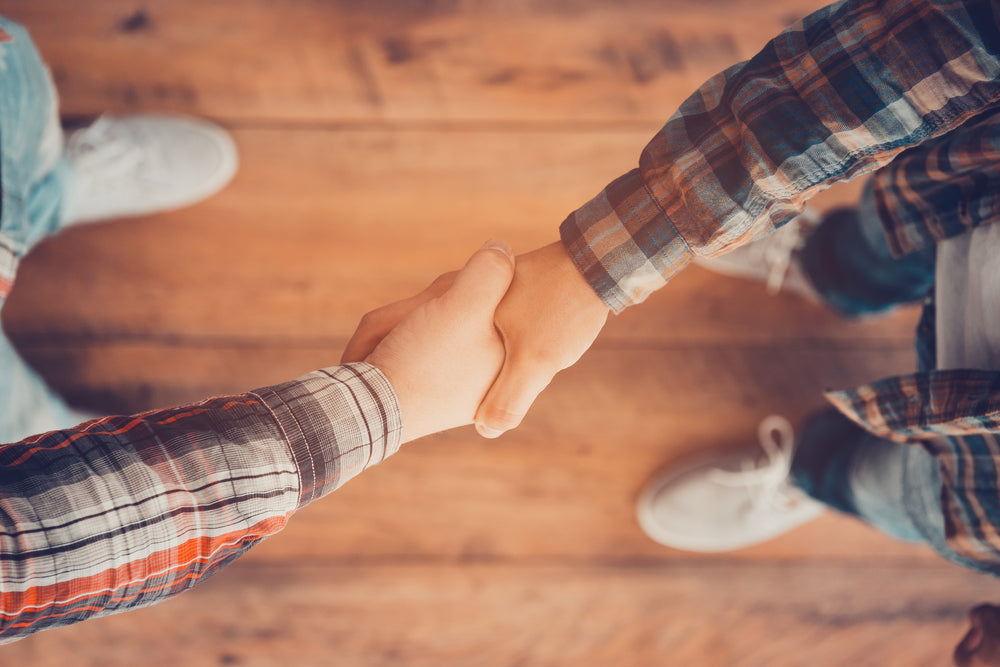 Top view of two men shaking hands while standing on the wooden floor