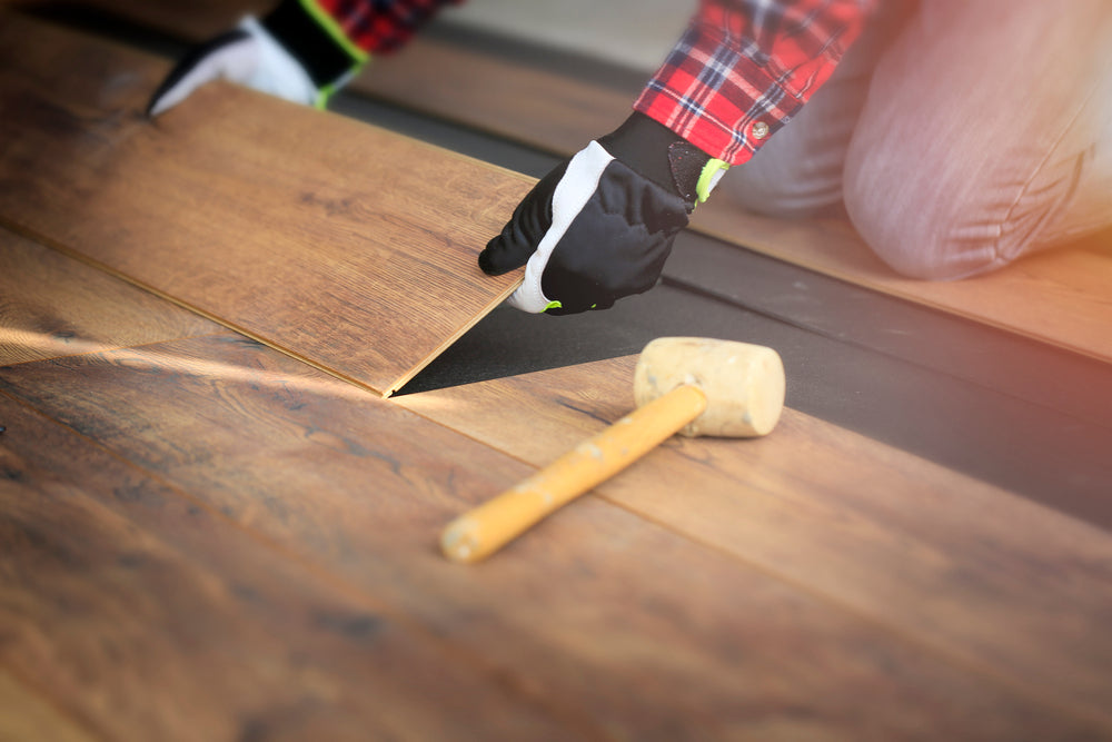 Worker hands installing a hardwood floor in the room