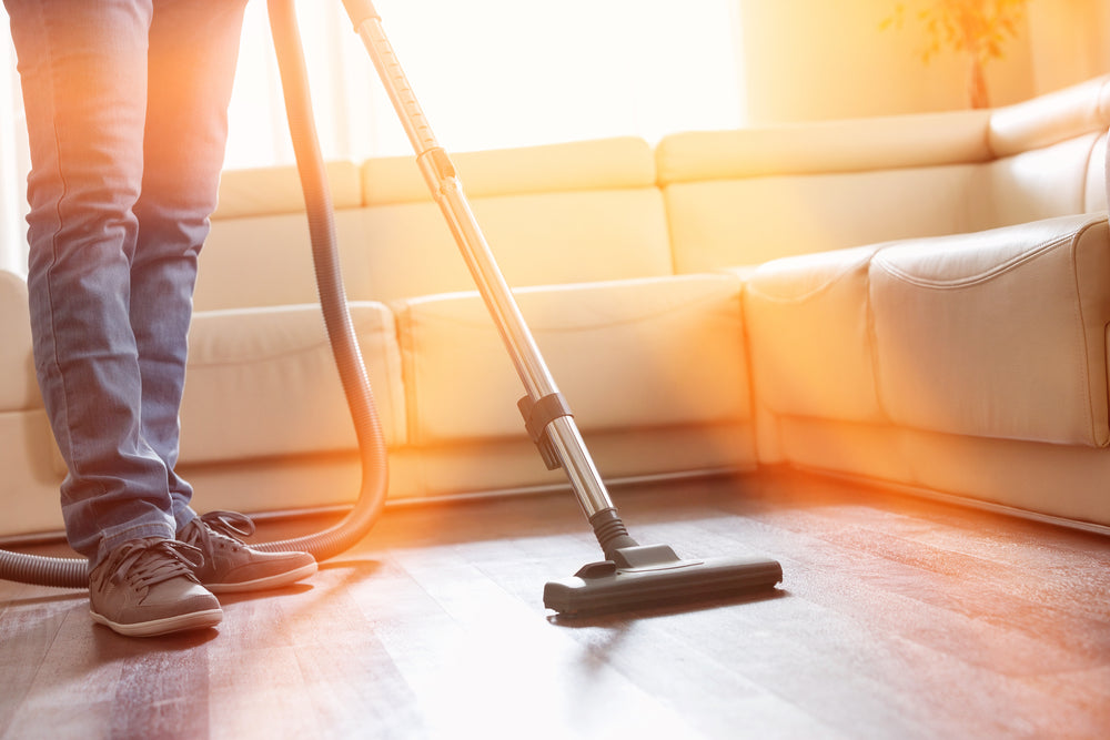 Low section of man cleaning hardwood floor with vacuum cleaner