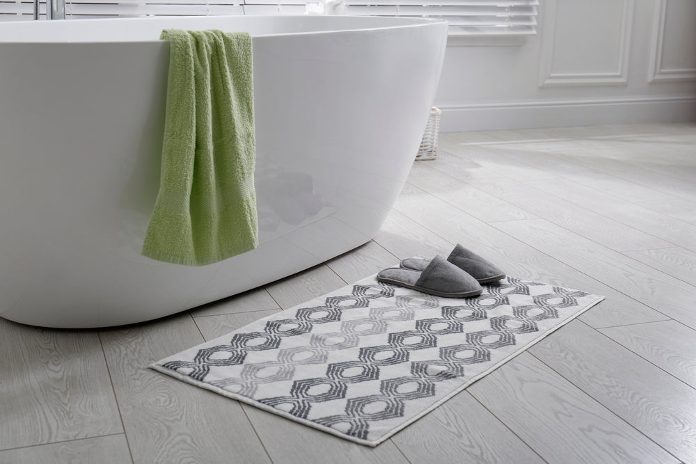 Stylish mat with slippers on floor near tub in bathroom. Interior design